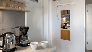 Une cuisine moderne équipée d’une machine à café, d’une bouilloire et de deux tasses posées sur le comptoir.