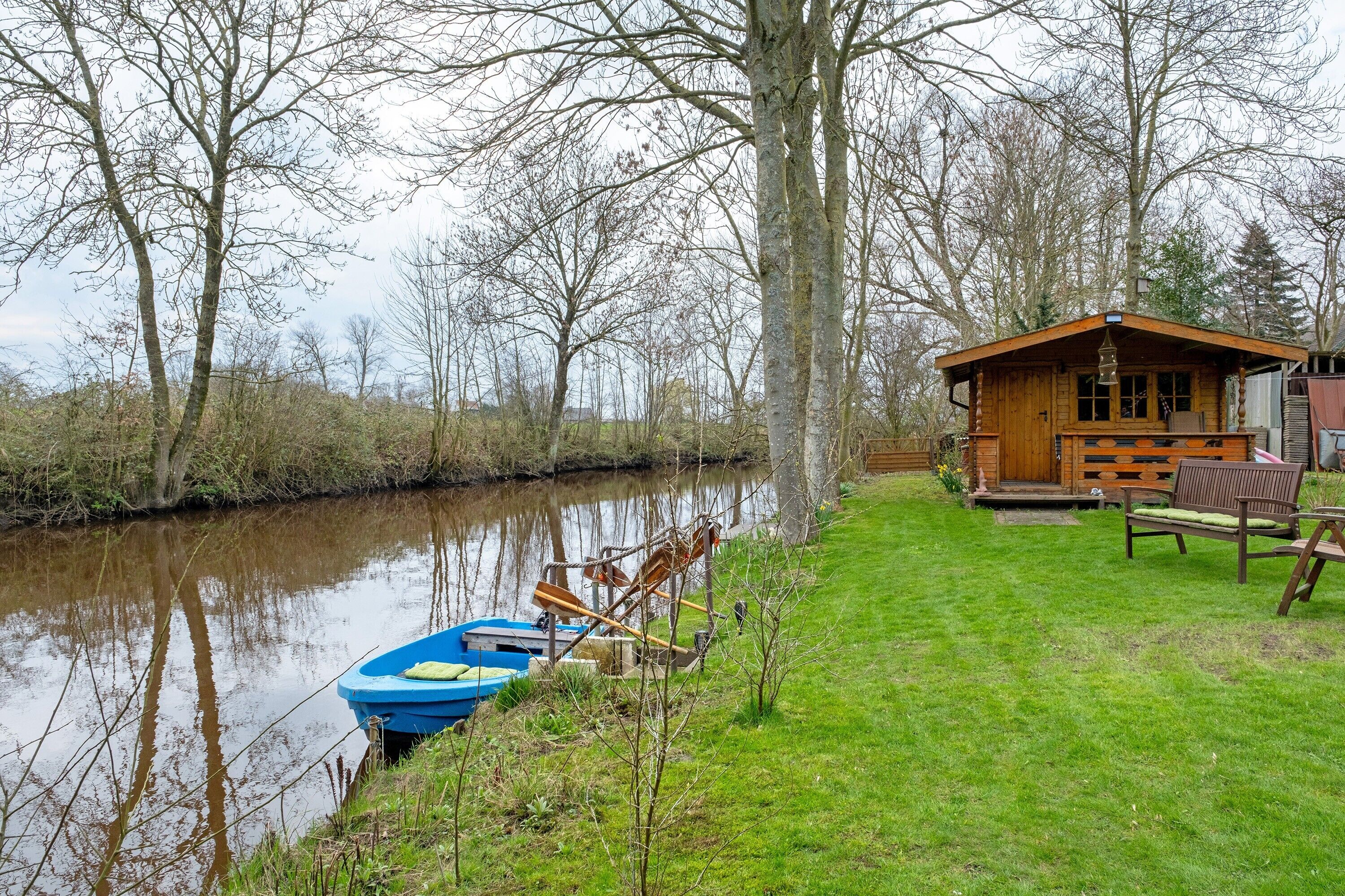 Eine Holzhütte am Flussufer mit einem angedockten Boot.