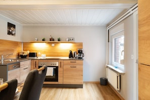 A compact kitchen with wooden cabinets, a microwave, a coffee maker, and a window.