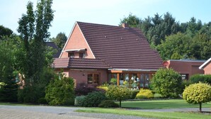 A two-story house with a sloped roof, brick exterior, and a front porch with a railing.