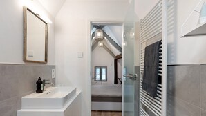 Un baño moderno con un espejo grande, un lavamanos y una zona de ducha.