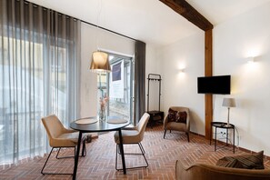 Un salon moderne avec un sol décoré d’un motif en briques, une table de salle à manger ronde entourée de chaises, un canapé, un téléviseur et une lampe.
