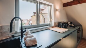 A kitchen with a large window, a sink, a countertop, and a coffee machine.