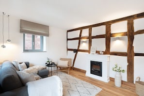 A modern living room with a fireplace, wooden beams, a sofa, a chair, and a small table. - Apartment "Altes Pfarrhaus - Studio" with Shared Terrace & Wi-Fi (Gleisweiler)