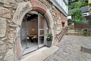 A stone building with a large arched doorway, a potted plant, and a brick pathway. - Apartment "Altes Pfarrhaus - Studio" with Shared Terrace & Wi-Fi (Gleisweiler)