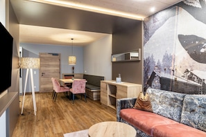 A modern interior with a dining area, a sofa, and a large wall mural.