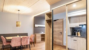 Une cuisine moderne avec des meubles en bois et une cuisinière encastrée, un coin repas avec une table et des chaises, et un luminaire suspendu.