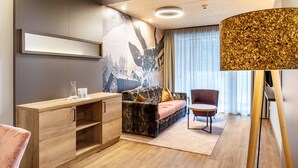 Une pièce moderne comprenant un canapé, un meuble en bois, une table ronde et un grand lampadaire.