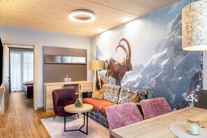 Ein modernes Wohnzimmer mit einer Wandmalerei zum Thema Berge, einer Holzzahlendecke, einem Sofa, einem Tisch und einer Lampe.