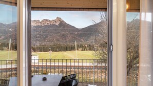 Ein Balkon mit Tisch und Stühlen, Blick auf die Berge und eine Umzäunung.
