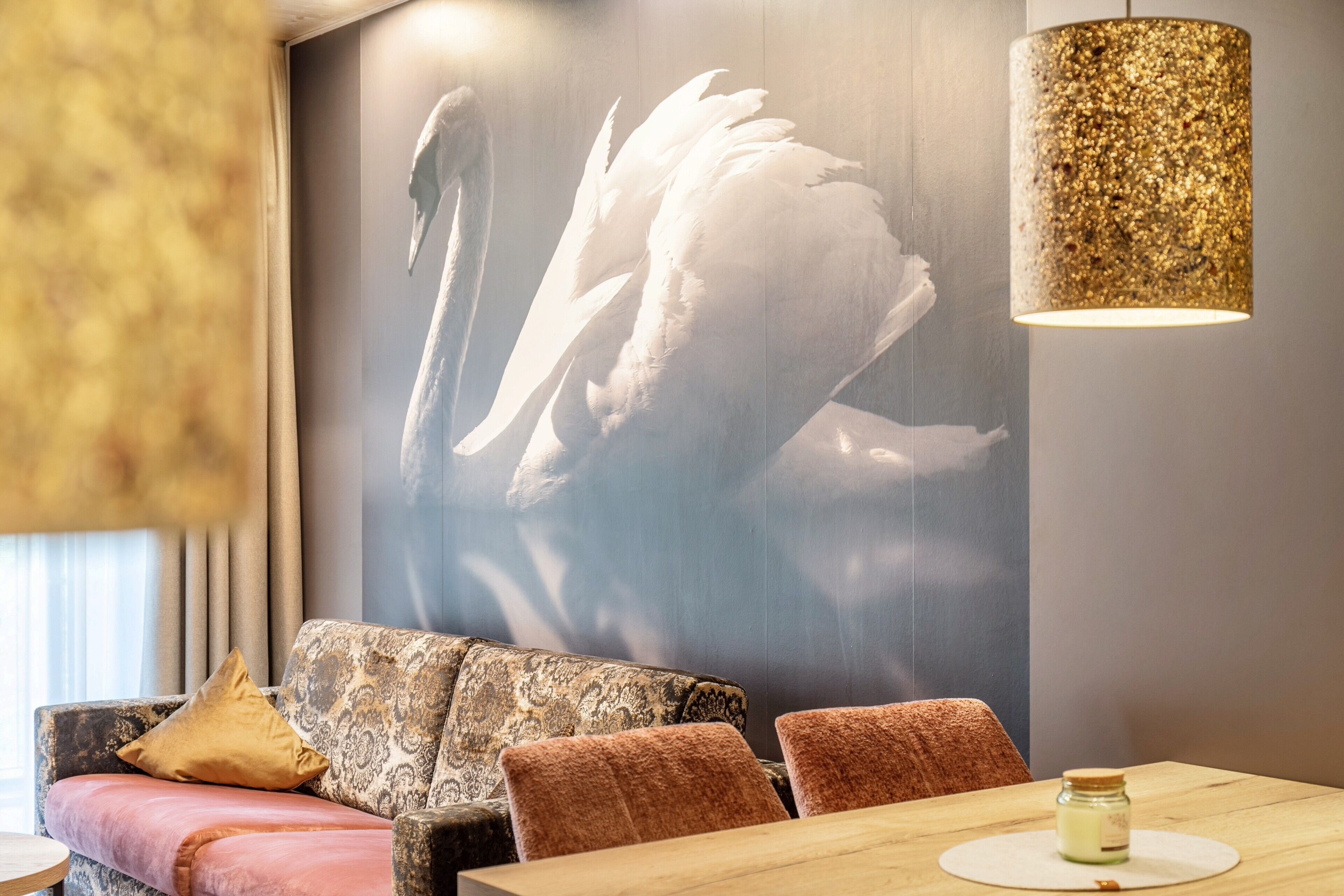 A modern interior with a patterned sofa, a dining table with a candle, and a wall-mounted lamp.