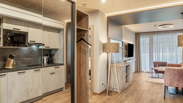 Una cocina moderna con electrodomésticos integrados, un comedor con mesa y sillas, y un ventanal con cortinas.