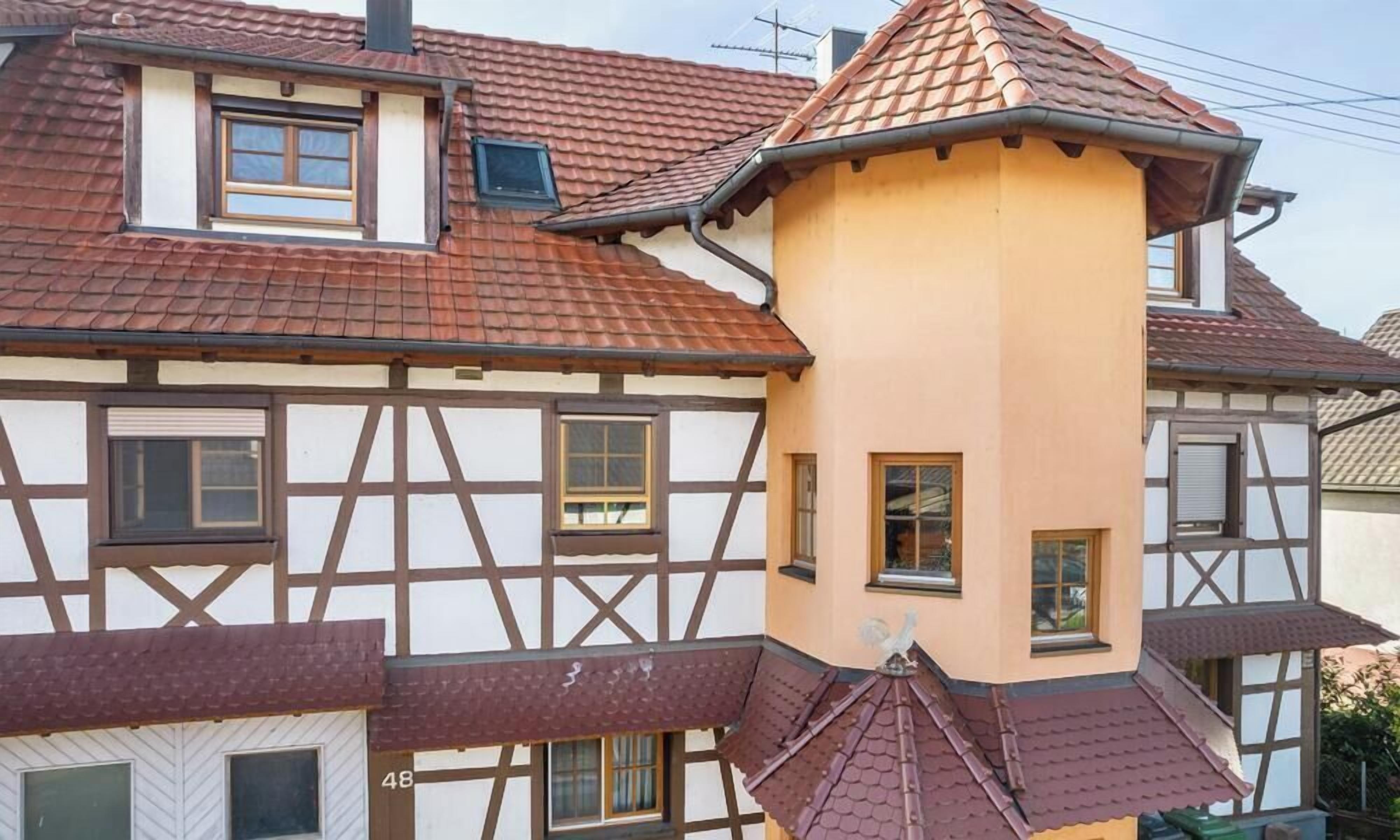A traditional half-timbered house with a distinctive corner turret and a red-tiled roof.