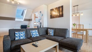 En moderne stue med en modulsofa, et sofabord og et spiseområde med et træbord og stole.