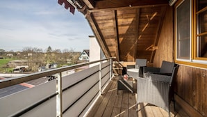 En træterrasse med udsigt over landskabet, en fletstol og et lille bord.