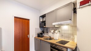 Eine kleine Küche mit Holzarbeitsplatte, integriertem Backofen und grauen Schränken.