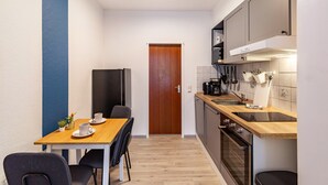 Eine kleine Küche mit Holztisch, Stühlen, einem Kühlschrank und einem Herd.