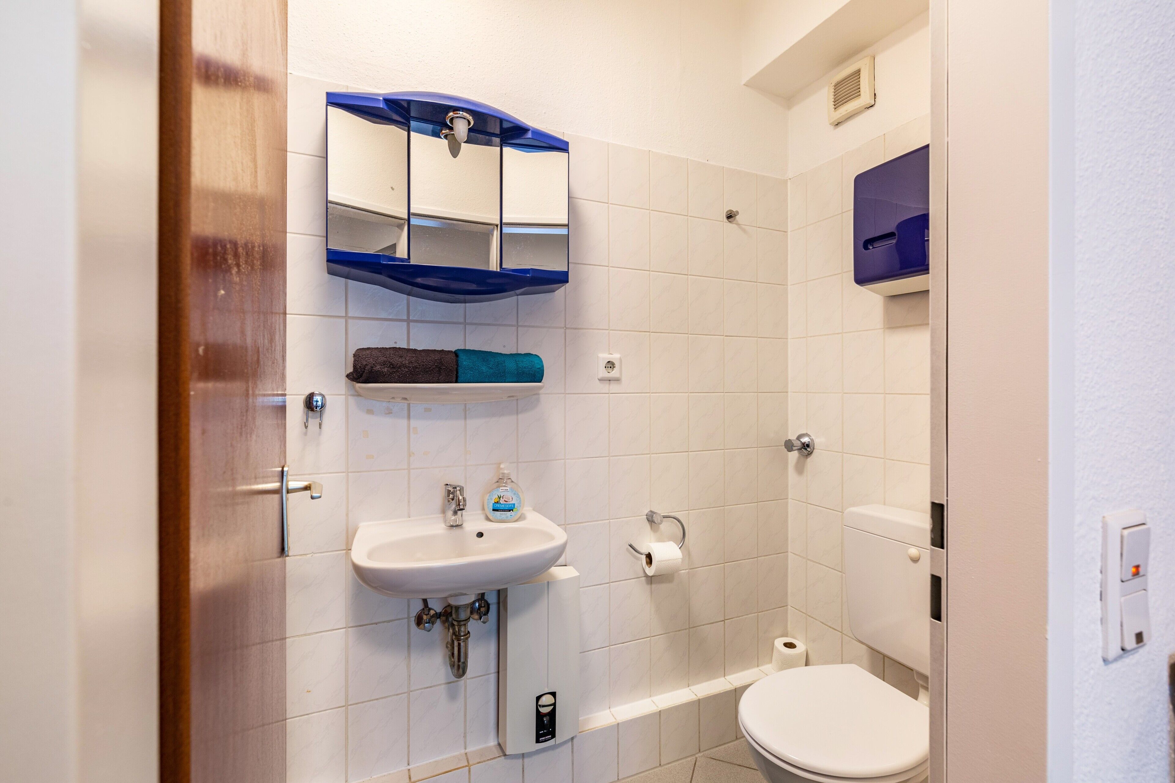 Ein Badezimmer mit Waschbecken, Spiegel, Toilette und Handtuchhalter.