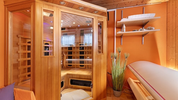 Una sauna in legno con porta in vetro, una panchina e uno scaffale con asciugamani.