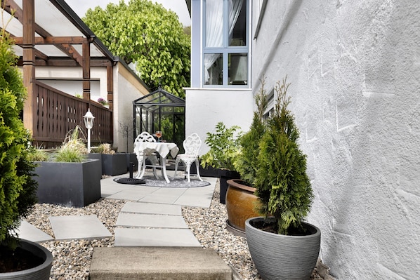 A patio area with a table and chairs, potted plants, and a pergola structure.