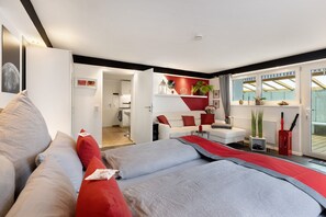 Habitació d'hotel moderna amb llit, sofà, taula petita i finestra amb vista.