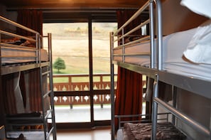 Une chambre avec des lits superposés donnant sur une terrasse en bois et une clôture.