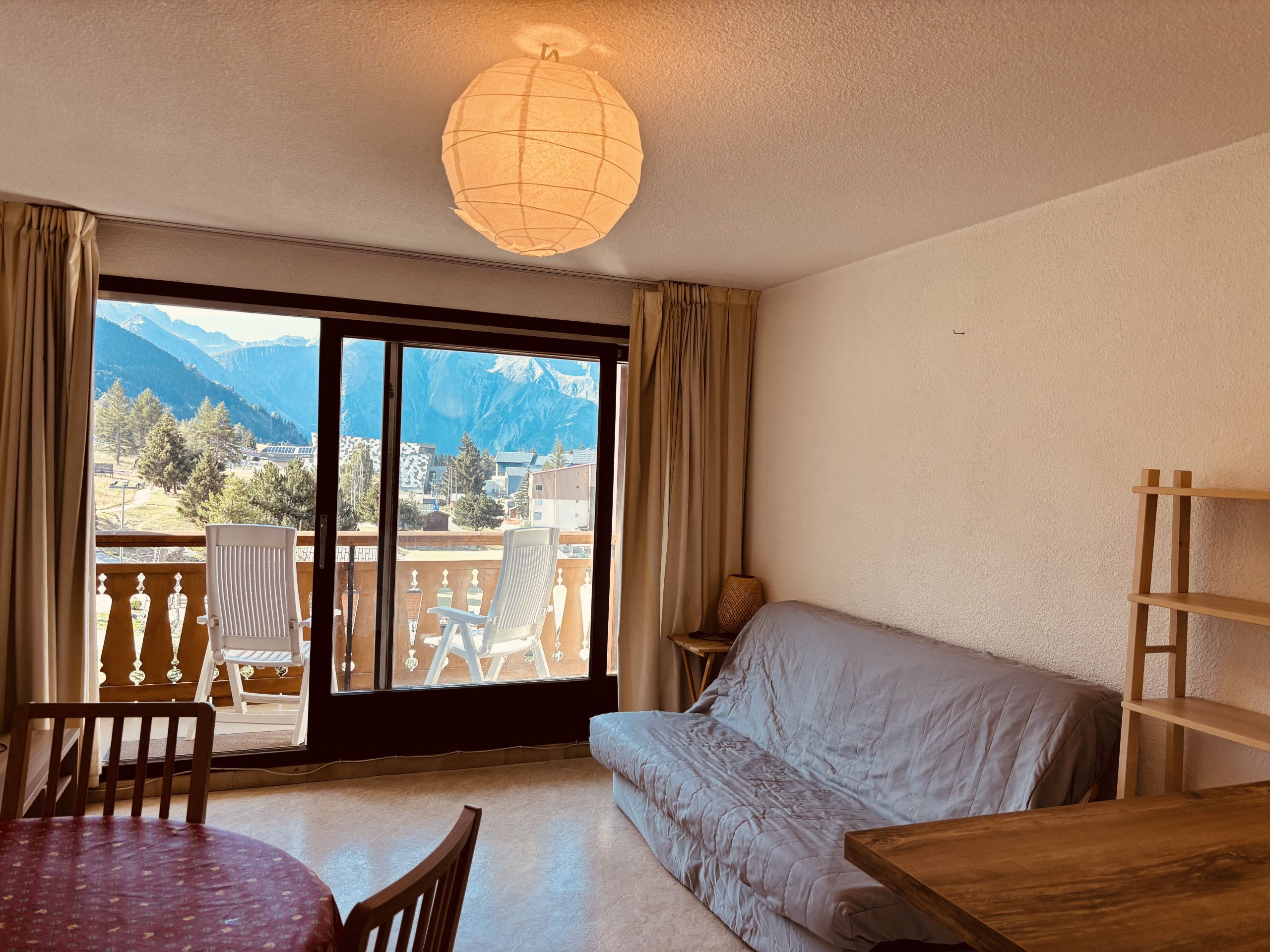A room with a balcony, a sofa, a dining table, and chairs.