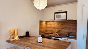 Une cuisine dotée d’un plan de travail en bois, de meubles blancs, d’un four à micro-ondes et d’un luminaire suspendu.