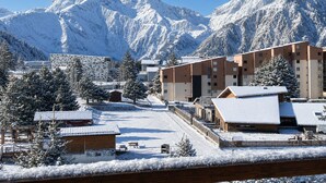 Une station de montagne enneigée, dotée de bâtiments modernes, d’une piste de ski et offrant un ciel dégagé.
