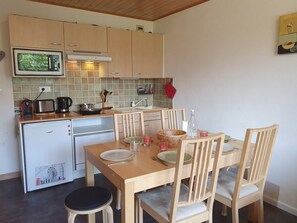 A compact kitchen with a microwave, toaster, kettle, and a small refrigerator.