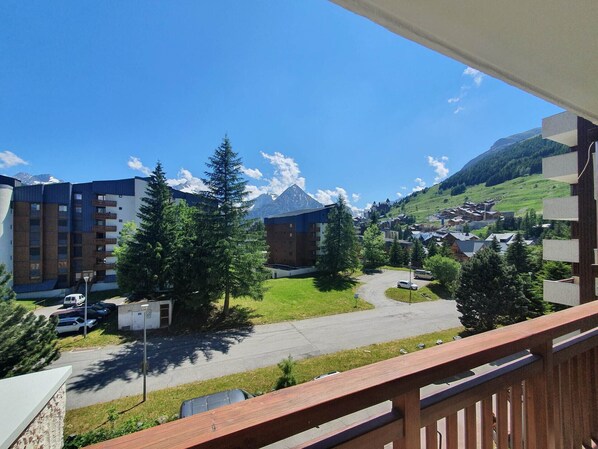 A hotel with a view of mountains, a parking area, and a small courtyard with trees.