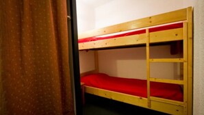A bunk bed with a red mattress in a room with a curtain.