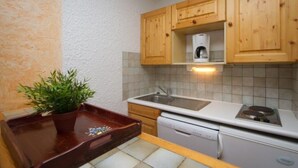 A compact kitchen with wooden cabinets, a sink, a dishwasher, and a countertop.