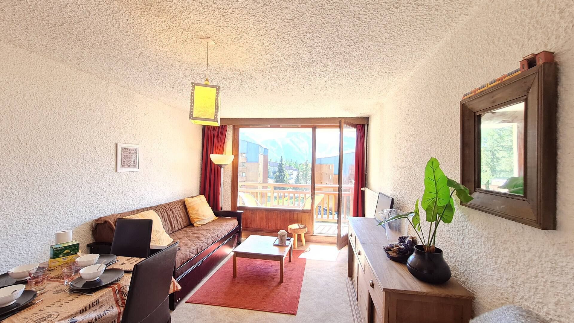 Een woonkamer met een bank, salontafel, eettafel en een balkon met uitzicht.