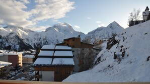 A snow-covered mountain village with traditional buildings, a wooden fence, and a clear sky. - Studio 3 ppl, balcony, near from the ski station (Les Deux Alpes)