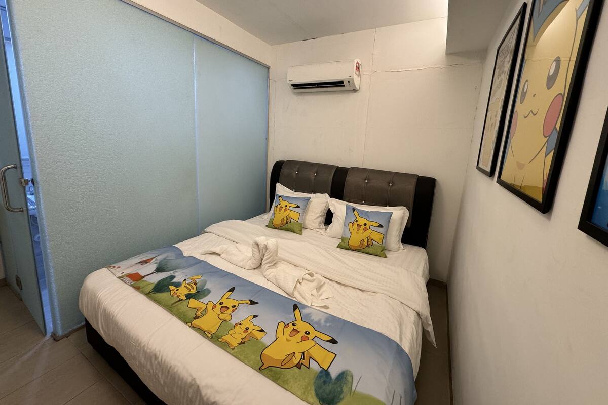 A bedroom with a bed, pillows, and a wall-mounted air conditioner.