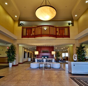 A spacious lobby with a high ceiling, a central seating area, and a staircase leading to an upper level. - Sweetwater Lodge (Rock Springs)