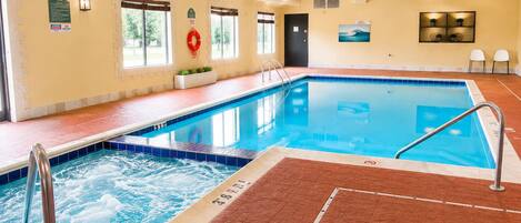 An indoor swimming pool with a hot tub, tiled walls, and a lifebuoy.