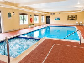 An indoor swimming pool with a hot tub, tiled walls, and a lifebuoy.