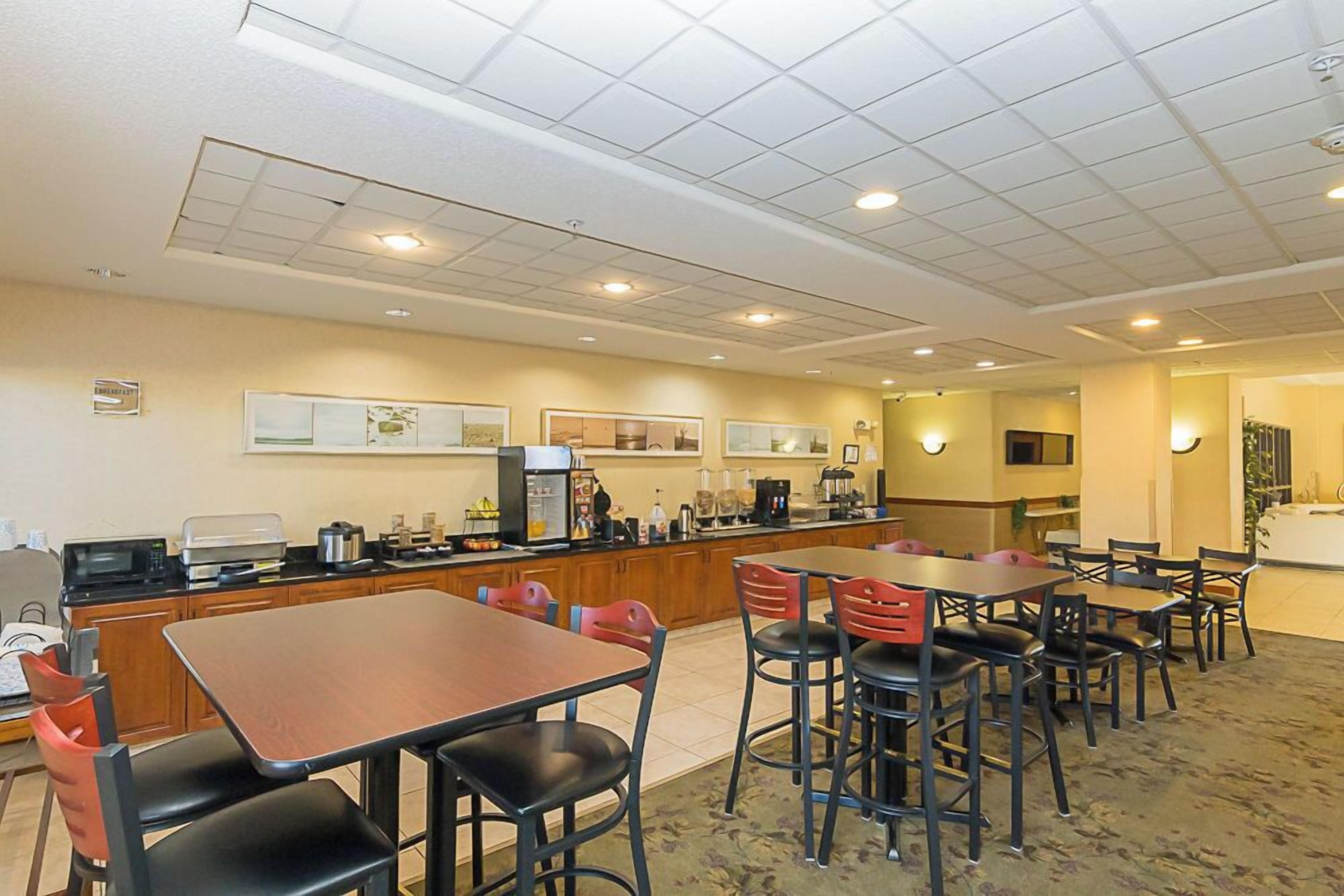 A hotel dining area with a long counter, multiple tables, and chairs.