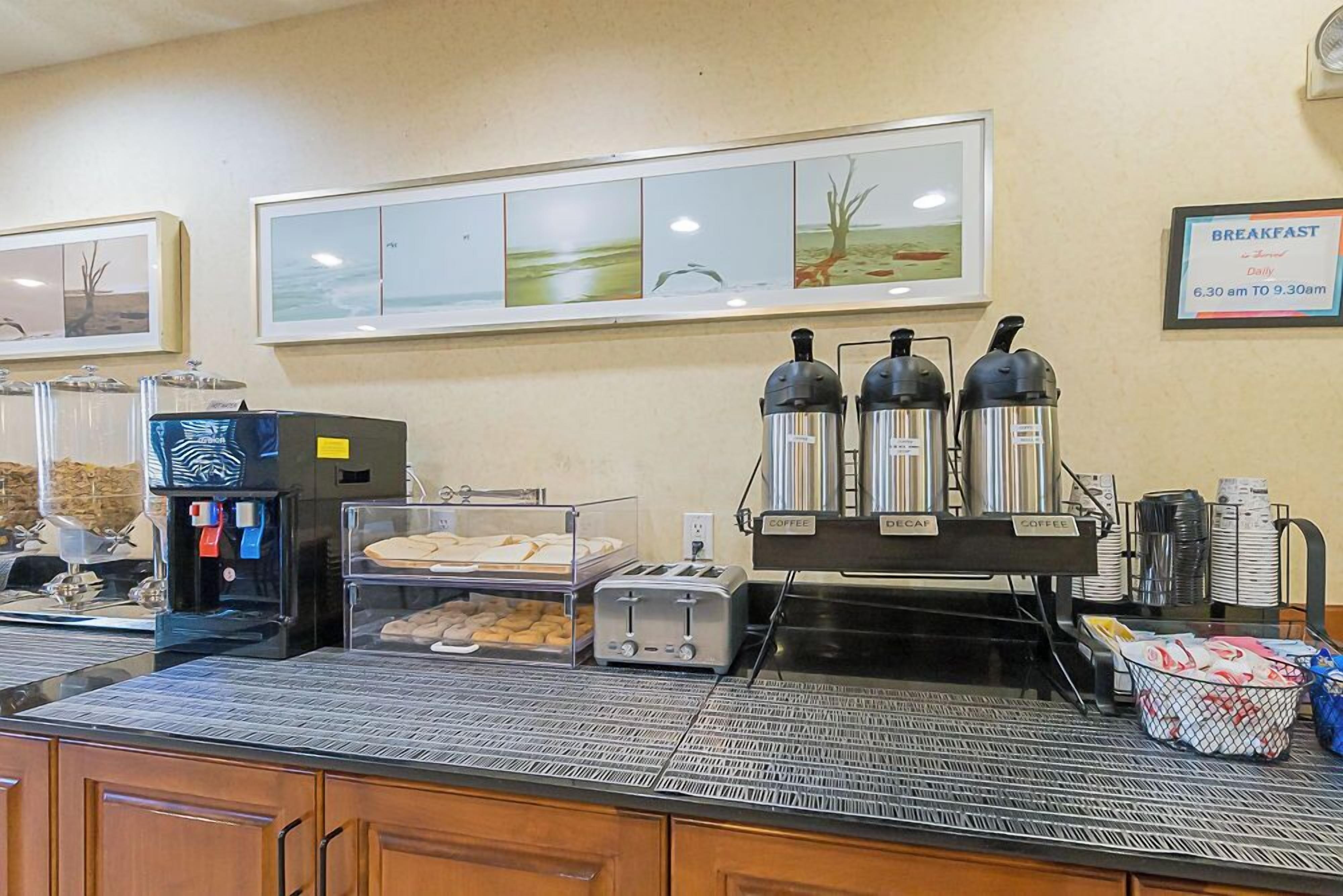 A breakfast area with coffee makers, a toaster, and a coffee dispenser.