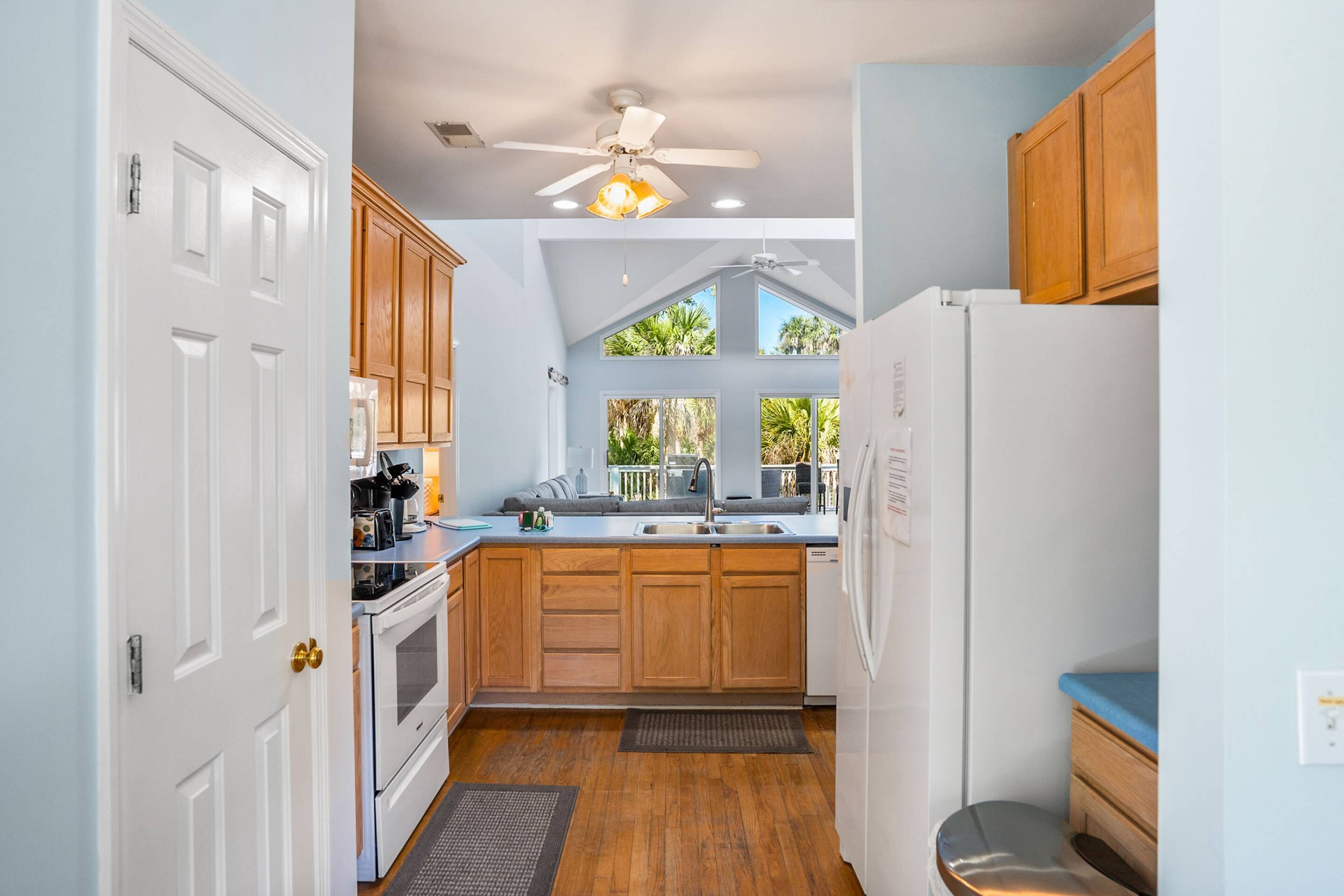 A kitchen with wooden cabinets, a white refrigerator, and a ceiling fan.