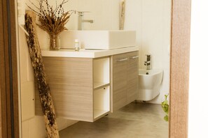 A bathroom with a white sink, wooden cabinets, and a plant.