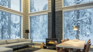 Una sala de estar moderna con chimenea, ventanas amplias, un sofá y un comedor.