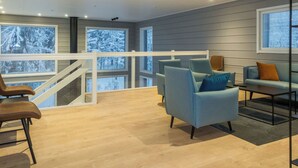 Una sala de estar moderna con una escalera, sofás azul claro y piso de madera.
