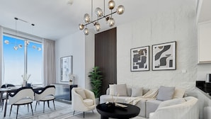 A modern living room with a sofa, chairs, a coffee table, and a dining area with a view.