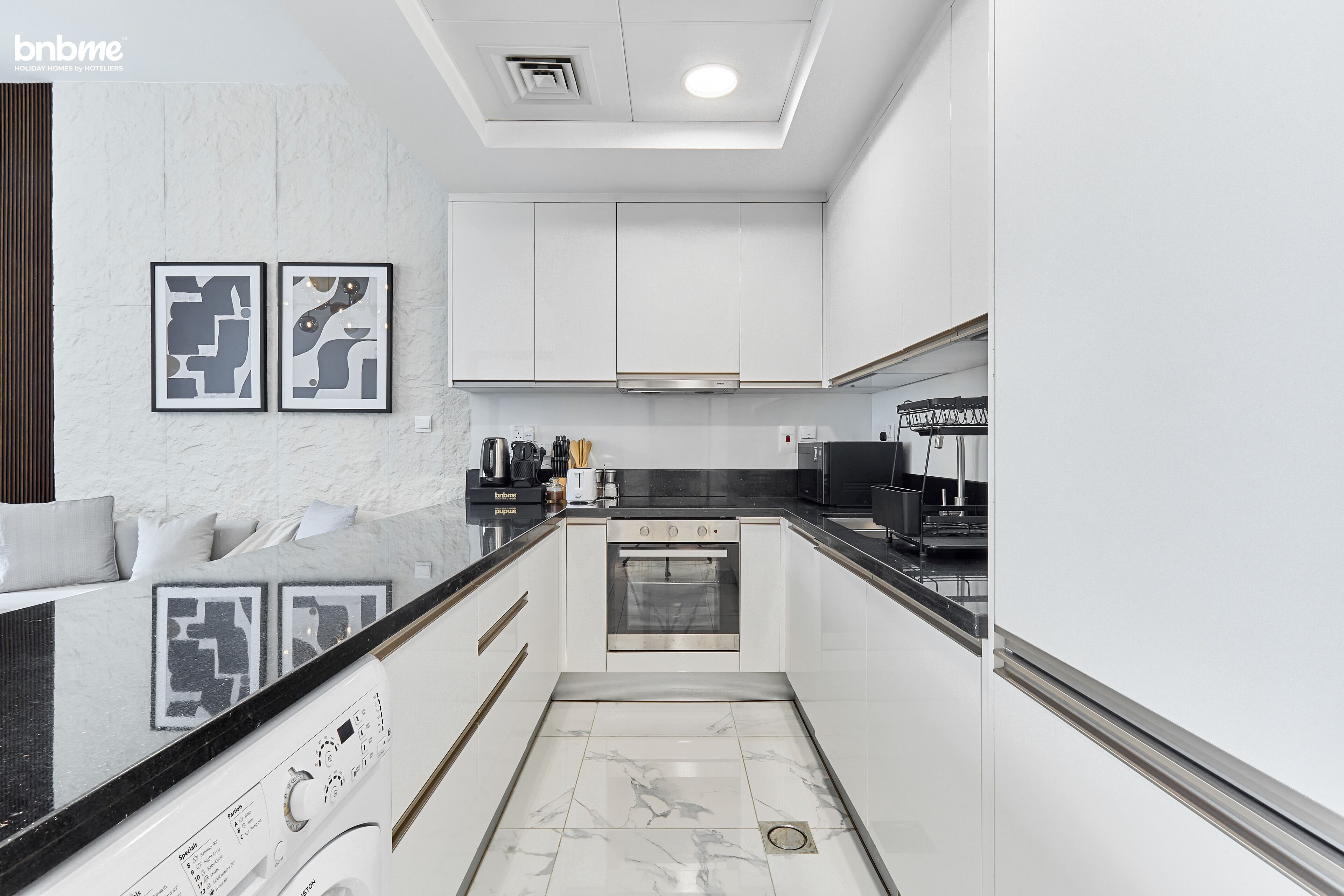 A modern kitchen with white cabinetry, a black countertop, and a built-in oven.