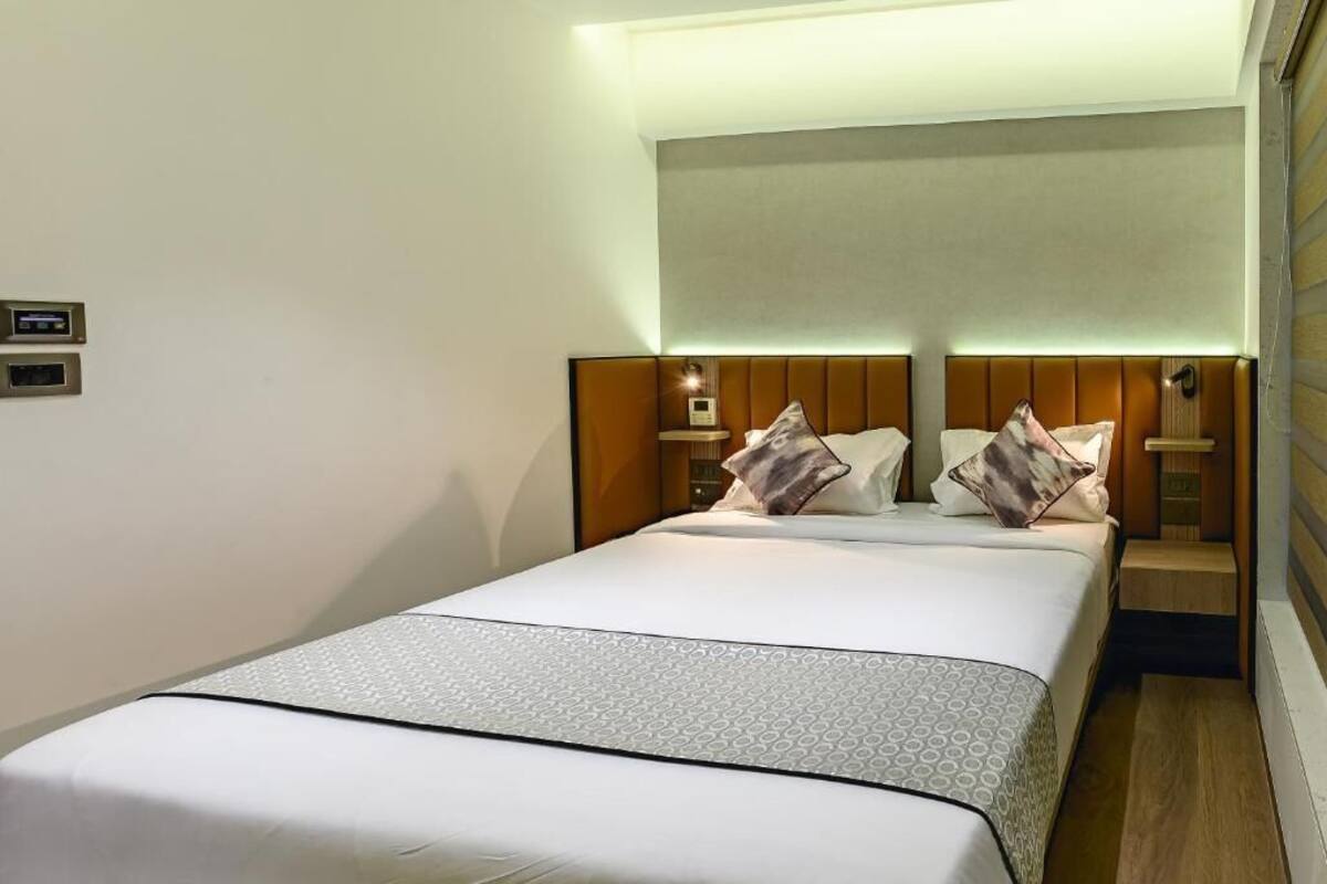 Une chambre d’hôtel avec un grand lit, deux tables de chevet avec des lampes et un panneau de commande fixé au mur.
