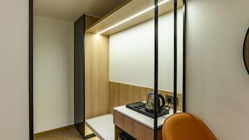 Una kitchenette compacta con una encimera, una tetera y una silla.