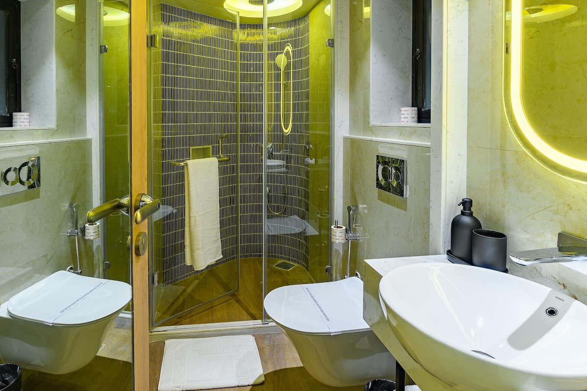 Une salle de bain moderne avec deux vasques, une douche à l’italienne et un mur recouvert de carreaux de marbre.